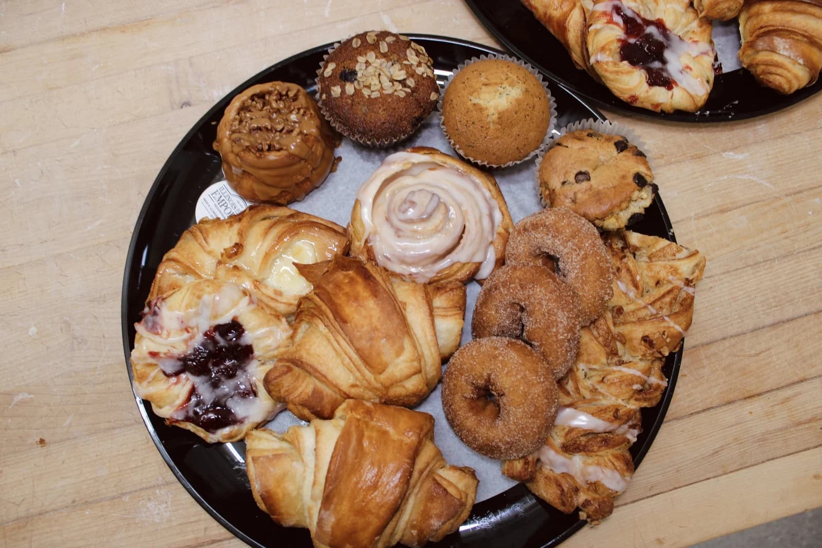 A tray of danish, croissants, a cinnamon roll, muffins, a scone and cinnamon-sugar donuts
