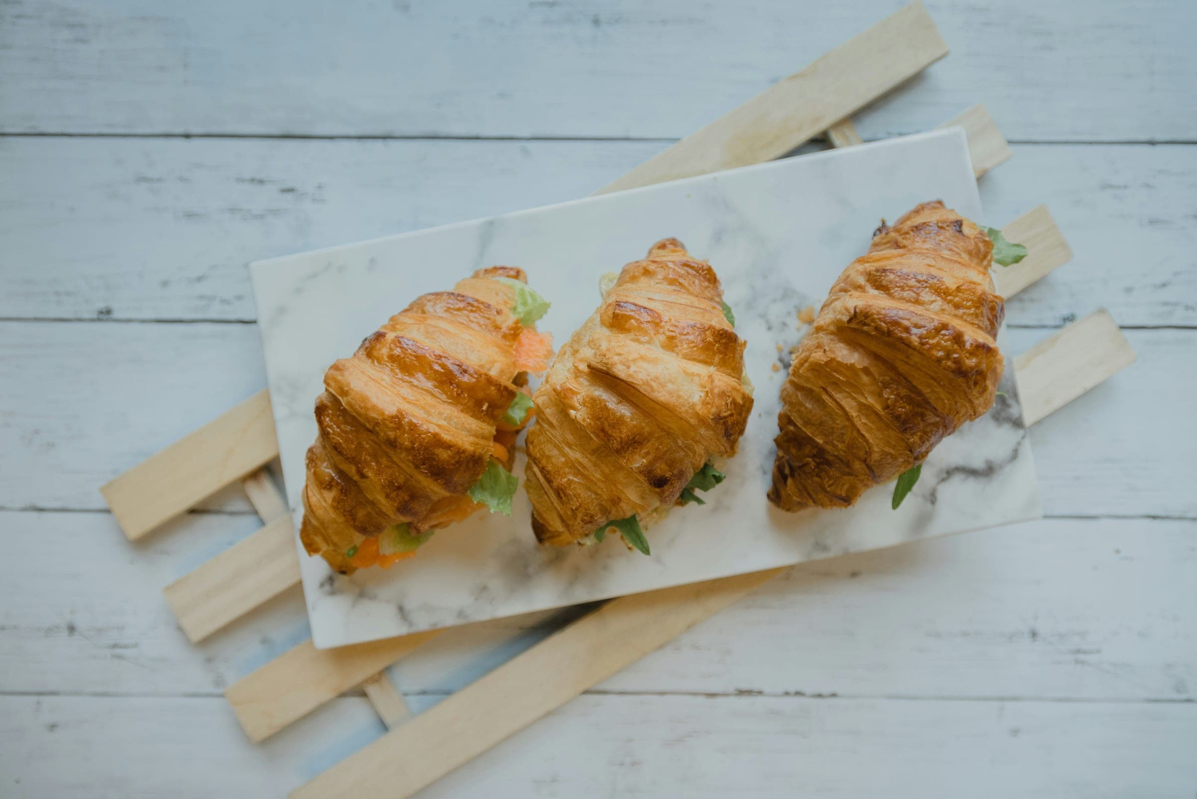 Croissant sandwiches on a marble serving board, the kind packed for a catering order
