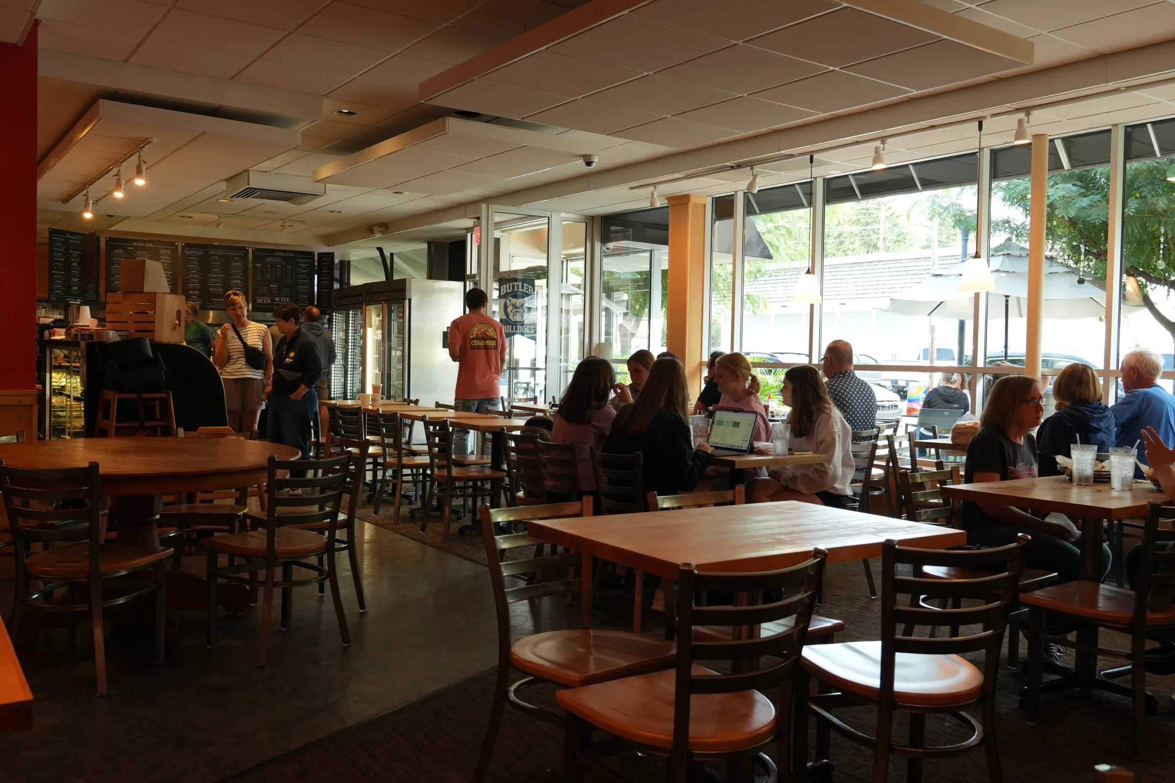 The dining room at Illinois Street Food Emporium, tables full under the menu boards